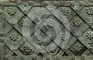 Ancient forged metal texture with decorative overlays. Doors, gates, shutters. Detail of a medieval gray door with metal decoratio