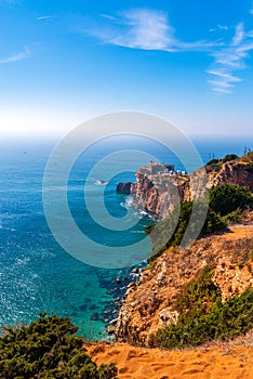 Ancient fort at seaside of Portugal, Nazare. Lighthouse on the rocky cliff. Atlantic ocean coast shoreline. Slopes of promontory