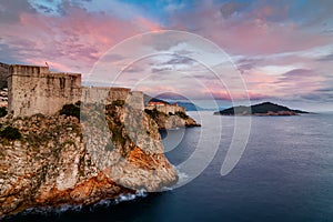Ancient fortress on the cliff edge of Dubrovnik at sunset with pink clouds