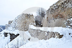 Ancient fortress wall and tower covered with snow, the wall is made of stone and limestone