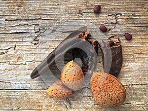 The ancient fruit of carobs and a bunch of almonds on a wooden background from
