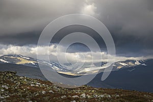Ancient glaciers landscape in sunlight under stormy and dramatic