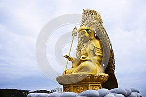 Ancient golden Jijang Bosal statue on stone rock cliffs for korean people travelers travel visit and respect praying blessing wish