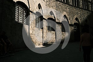 Ancient gray-stoned building with windows in Gothic style with the sunlight falling on it