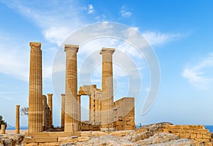 Ancient Greek pillars at Lindos acropolis with blue cloudy sky in the background