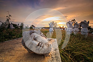 Ancient Head Buddha statue at sunset