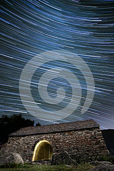ancient hermitage under star trails sky at night