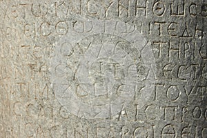 The ancient inscription is on the antique column or the wall. Ancient greek language