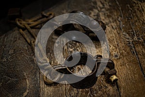 Ancient iron handcuffs on wooden floor from medieval times in England, prisoner wrist restraints.