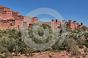 Ancient kasbah in morocco consisting of adobe houses and palaces and palmtrees oasis