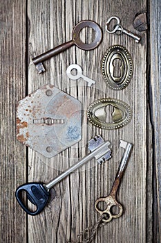 Ancient keys and keyholes on old wooden board