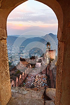 Ancient long wall with towers around Amber Fort through the arch of tower walls at morning. Rajasthan. India