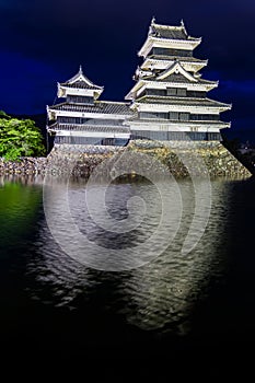 Ancient Matsumoto Castle at night with reflection in moat
