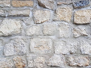 Ancient medieval stone masonry. Texture of a fragment of a wall of an old structure. A background for design and creative work.