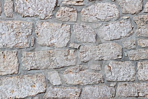 Ancient medieval stone masonry. Texture of a fragment of a wall of an old structure. A background for design and creative work.