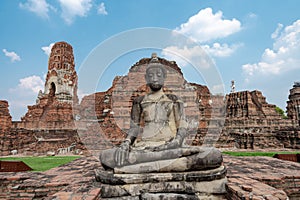 Ancient meditated Buddha statue in front of old red-brick ruins temple