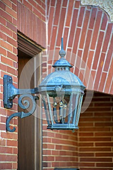 Ancient metal lampost on side of brick building facade on house or home industrial area for residential real estate