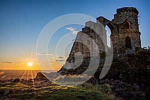 Ancient Mow Cop Castle at sunset with Sun star and blue sky in England