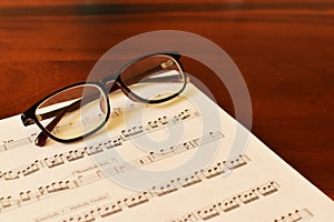 Ancient Musical Manuscript, Abstract Music Sheet and eye glasses on wooden table