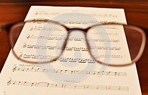 Ancient Musical Manuscript, Abstract Music Sheet and eye glasses on wooden table