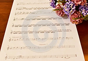 Ancient Musical Manuscript, Abstract Music Sheet and flowers on wooden table