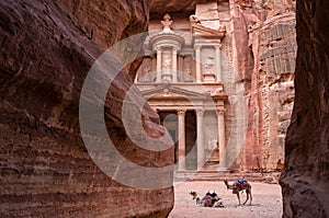 Ancient nabataean temple Al Khazneh Treasury located at Rose city - Petra, Jordan. Two camels infront of entrance. View from Siq