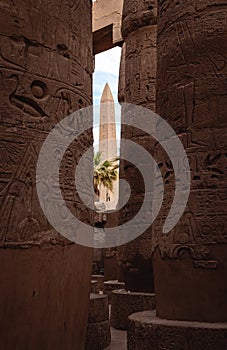 Ancient Obelisk through Stone Columns at Karnak Temple, Luxor Egypt