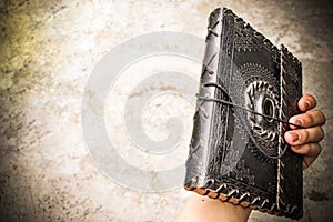 Ancient old leather bound book in the hand os a woman.