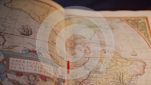 Ancient, open historical or geographic atlas with hand-painted maps. Lying on the table, close-up shot of the camera from the left