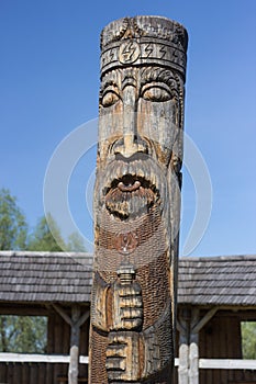 Ancient pagan temple with wooden idol and house from tree bars in ethnic style