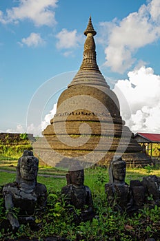 An ancient pagoda of the Mrauk U, Myanmar heritage in the back of small, damaged Buddha statues