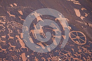 Ancient petroglyphs carved into a sandstone wall in the desert.