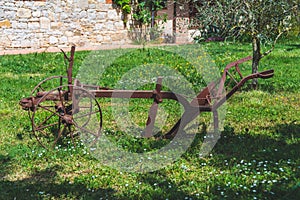 Ancient plow in rusty metal on a meadow