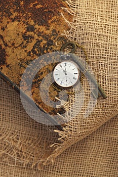 Ancient pocket watch and key on old folio half-covered with old sackcloth. Time passing concept. Knowledge eternity concept photo