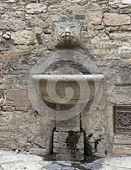 Ancient public fountain on an outside wall in Assisi, Italy.