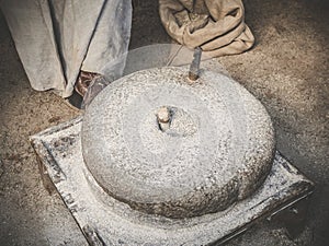 The ancient quern stone hand mill. Old grinding stones straw around