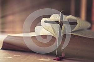 Ancient religious book and wooden cross on the background of a wooden photo