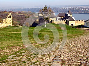 Ancient road paved with cobblestone and going to medieval fortress in Khotyn on hill above river.