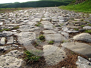 Ancient road paved with cobblestone and going up through hills.