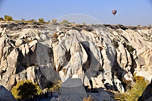 Ancient Rock Dwellings in Goreme, Cappadcia, Turkey, with hot air balloon above.