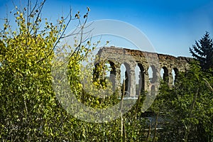 Ancient roman aqueduct ouside Rome, surrounded by trees