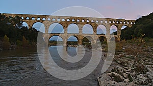 Ancient Roman aqueduct Pont du Gard crossing Gardon river after sunset near Vers-Pont-du-Gard, Occitanie, France.