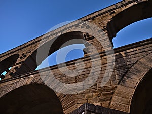 Ancient Roman aqueduct Pont du Gard with stone arches after sunset near Vers-Pont-du-Gard, Occitanie, France with clear sky.