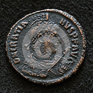 Ancient Roman coin of Emperor Gratian, top view of vintage metal money isolated on black background. Concept of old texture, Rome