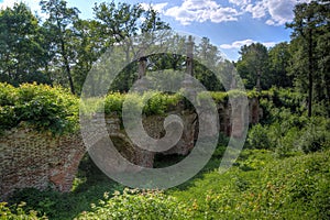 Ancient ruined overgrown red brick bridge in the forest