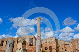Ancient ruins of buildings from roman times. Ostia Antica in Italy, historic walls and columns with light blue sky, white clouds
