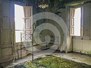 Ancient rusty iron bed in an abandoned and ruined room