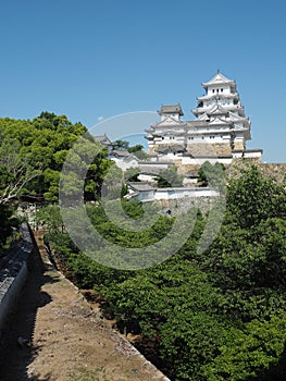 Ancient samurai castle in Himeji city in Japan with white walls, dark tile roofs and stone walls on a sunny day in summer with blu