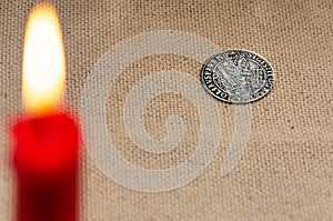Ancient silver coin and burning candle