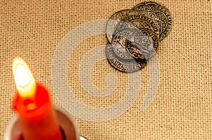 Ancient silver coins and burning candle